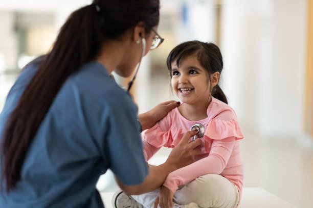 A female doctor uses her stethoscope to check her young patient's heart health.